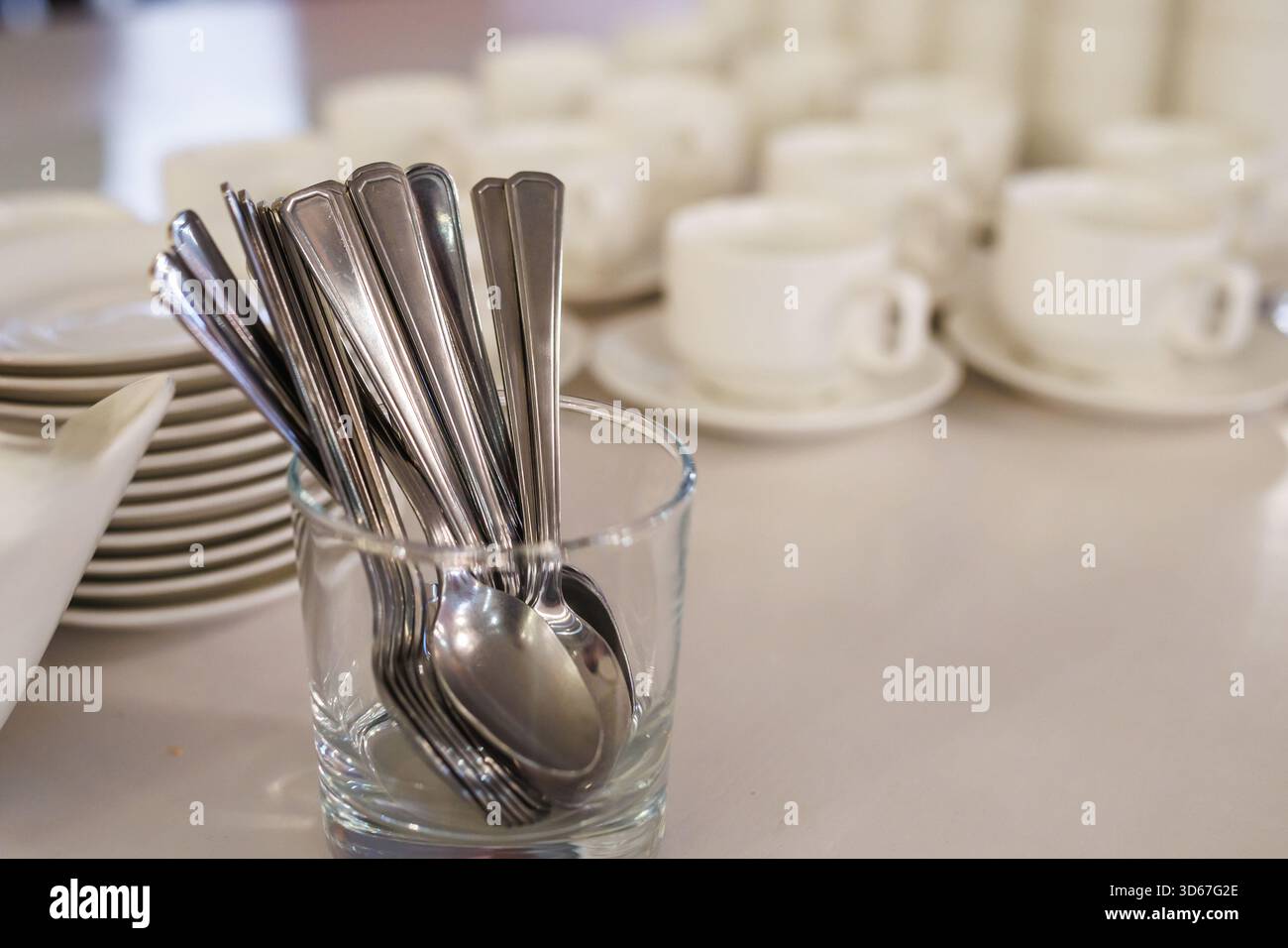 Tassen, Untertassen, Löffel für Teezeremonie auf einem Banketttisch Stockfoto