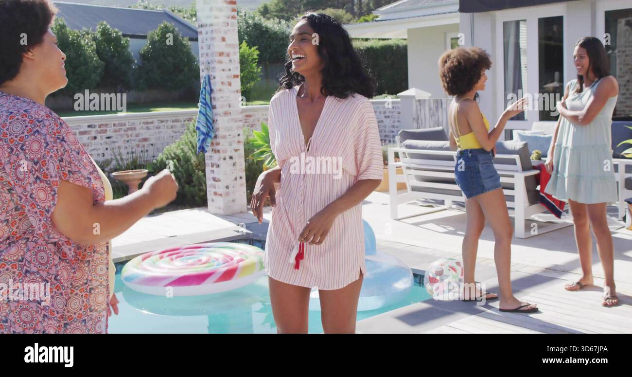Lachende Frau in gestreiftem Kleid, die roten Gegenstand auf Deck am Tauchbecken hält, mit Lutscher-Schwimmer Stockfoto