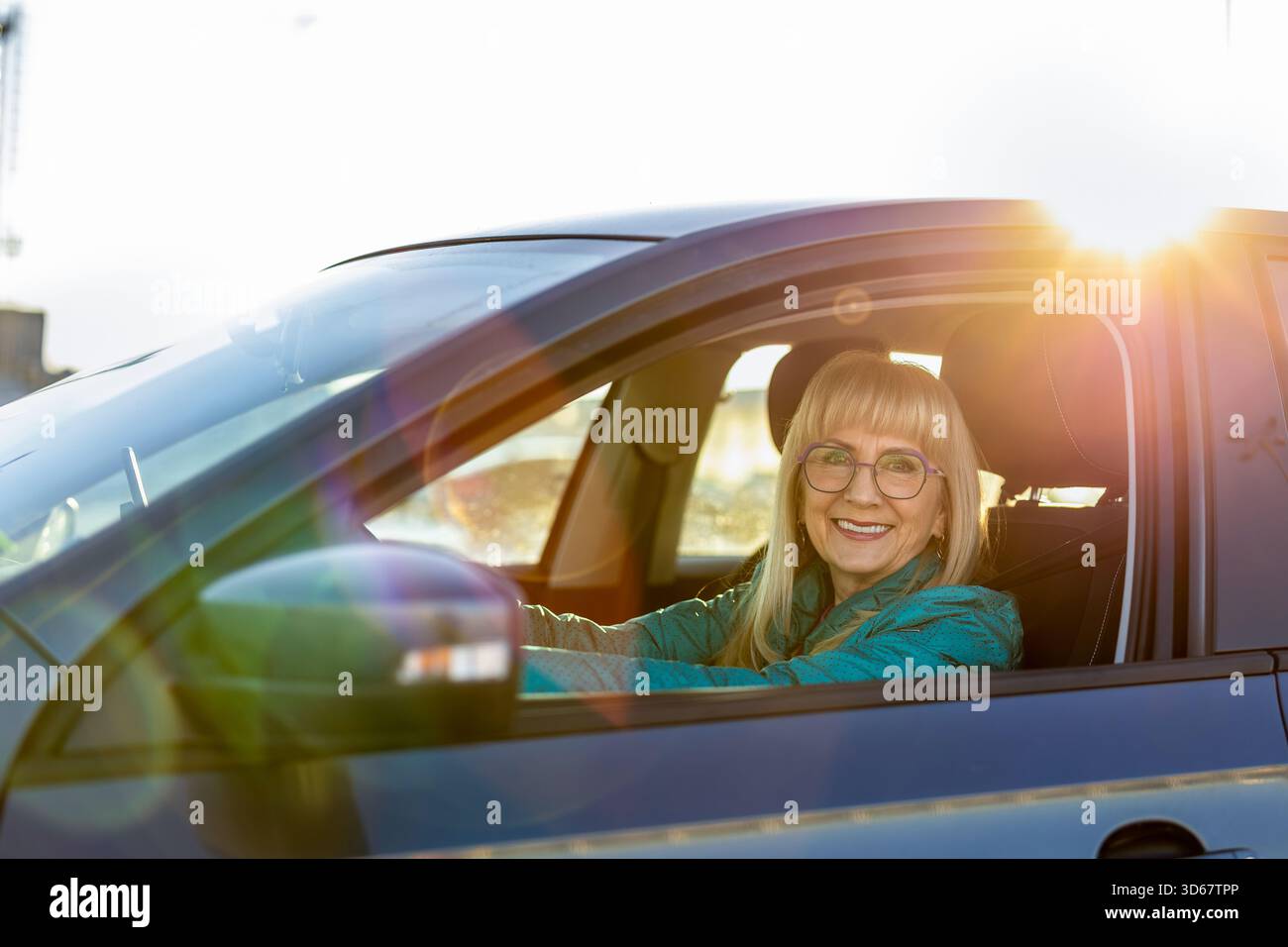 Reife Fahrerin lächelt hinter dem Steuer Stockfoto