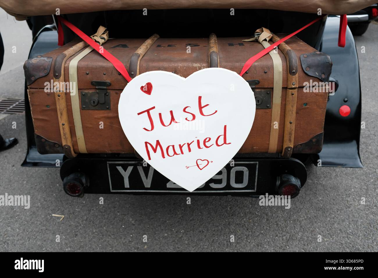 "Gerade geheiratenes Herzzeichen" auf dem Kofferraum eines alten Hochzeitswagens. UK. 2023. Stockfoto