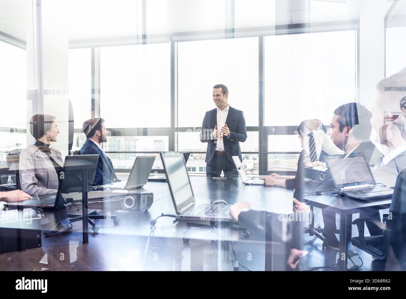 Erfolgreicher Teamleiter und Geschäftsinhaber, der informelle interne Besprechungen leitet. Geschäftsmann, der im Vordergrund an einem Laptop arbeitet. Konzept für Wirtschaft und Unternehmertum. || Modell freigegeben Stockfoto