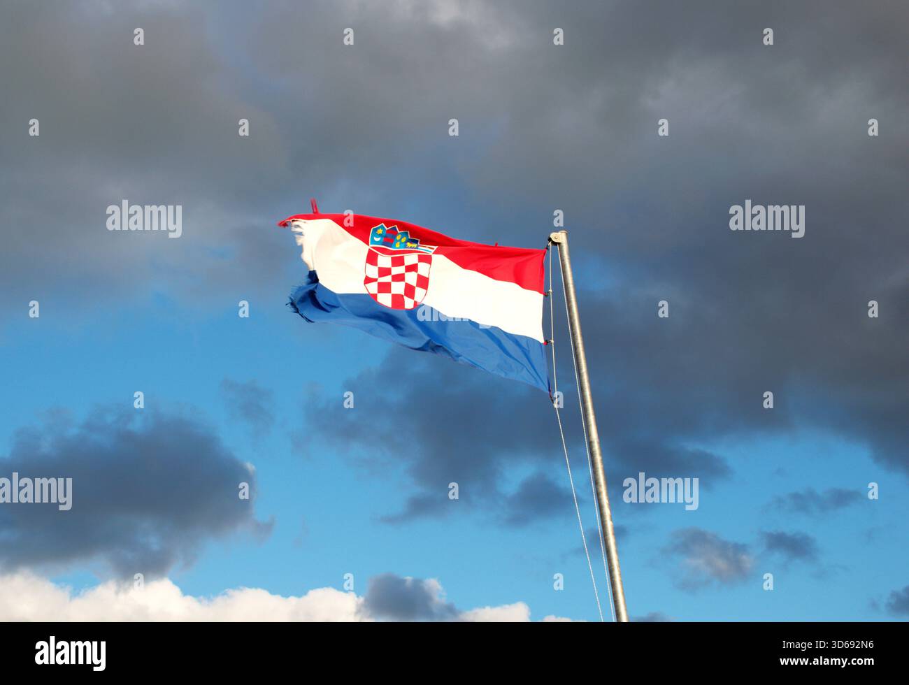 Lebendige kroatische Flagge mit Wappen, die bei starkem Wind unter einem dramatisch bewölkten Himmel winken. Patriotismus, nationale Identität, Europa, Reisen. Stockfoto