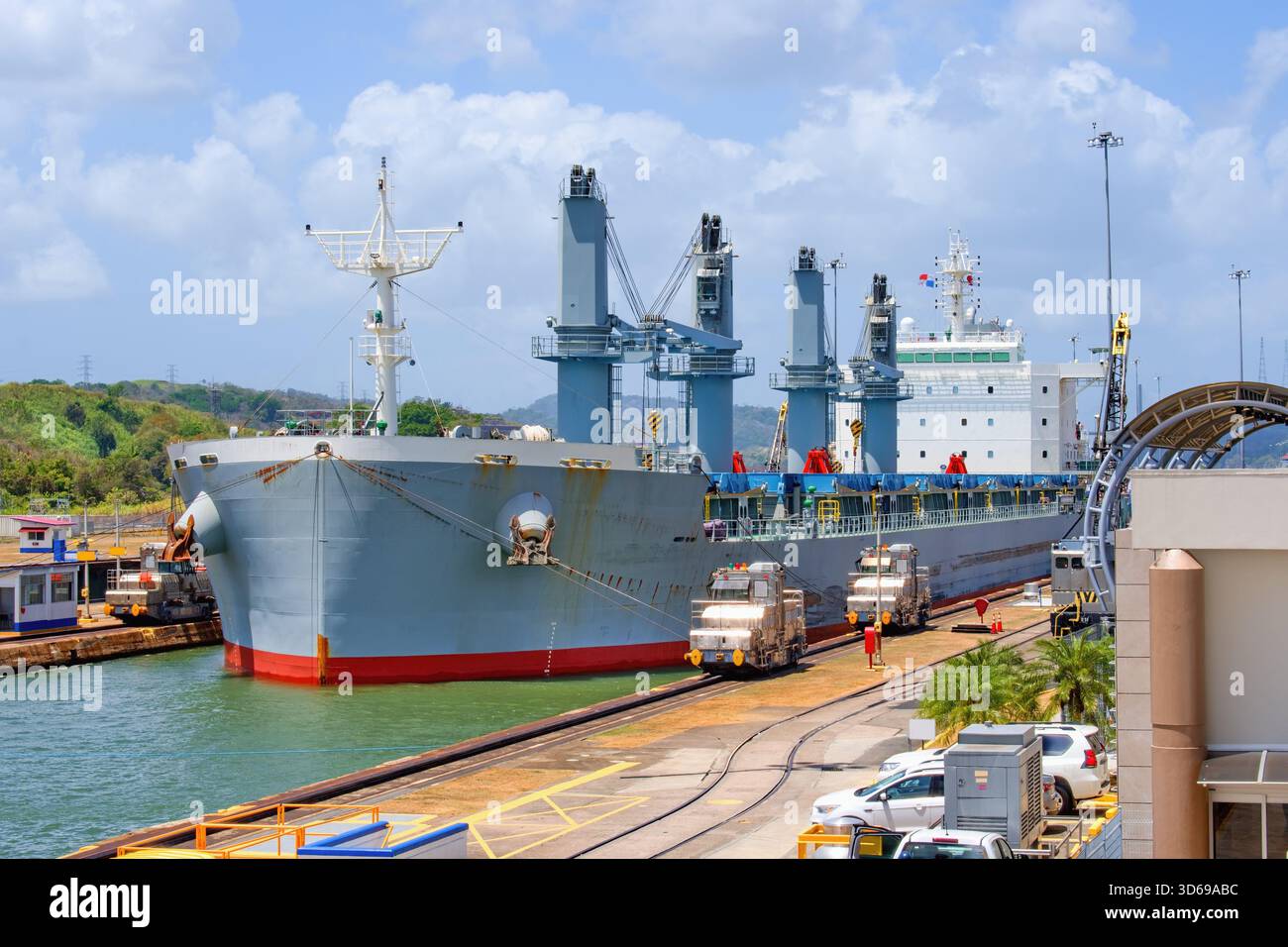 Großes Frachtschiff, das von speziellen Elektrolokomotiven im Panamakanal gezogen wird - Miraflores Schleusen vom Tribun des Besucherzentrums aus gesehen. Stockfoto
