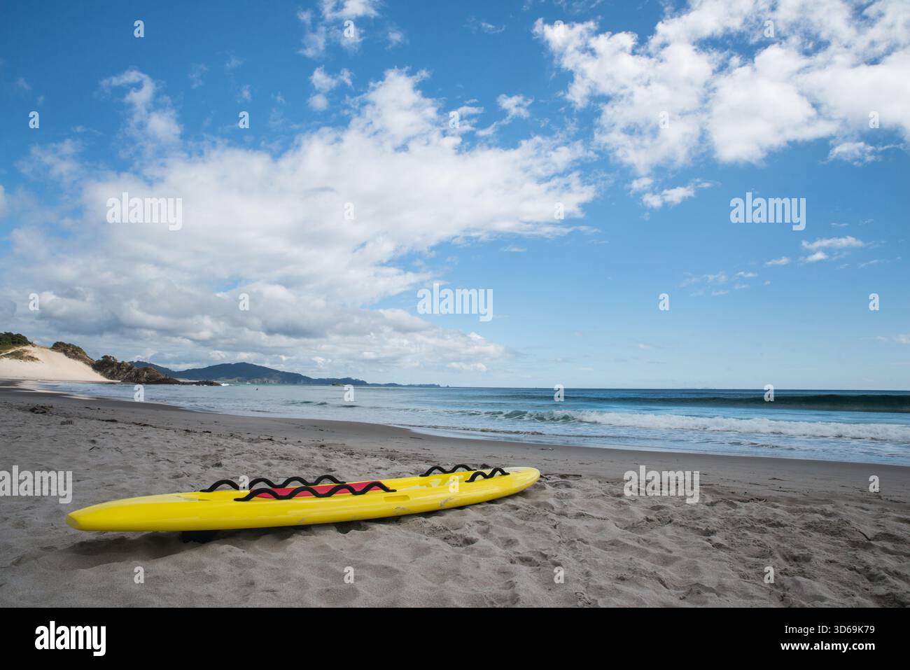 Ein gelbes Paddelbrett auf dem Sand am Ocean Beach, Whangarei Heads, Nordinsel, Neuseeland Stockfoto