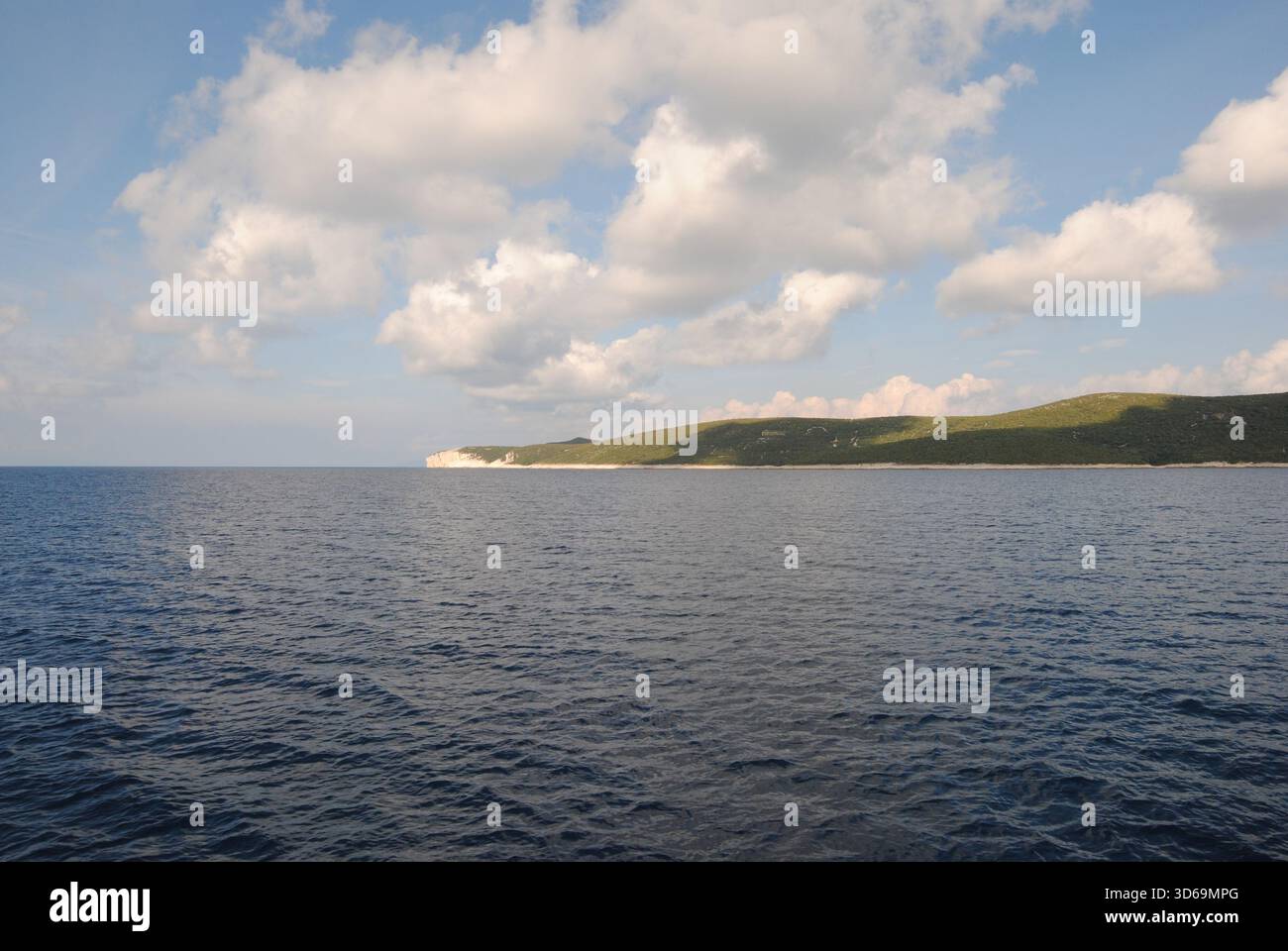 Panoramablick auf die Insel Unije mit einigen Lammwolken am Himmel und ihren Reflexionen auf dem Wasser der wunderschönen Adria Stockfoto
