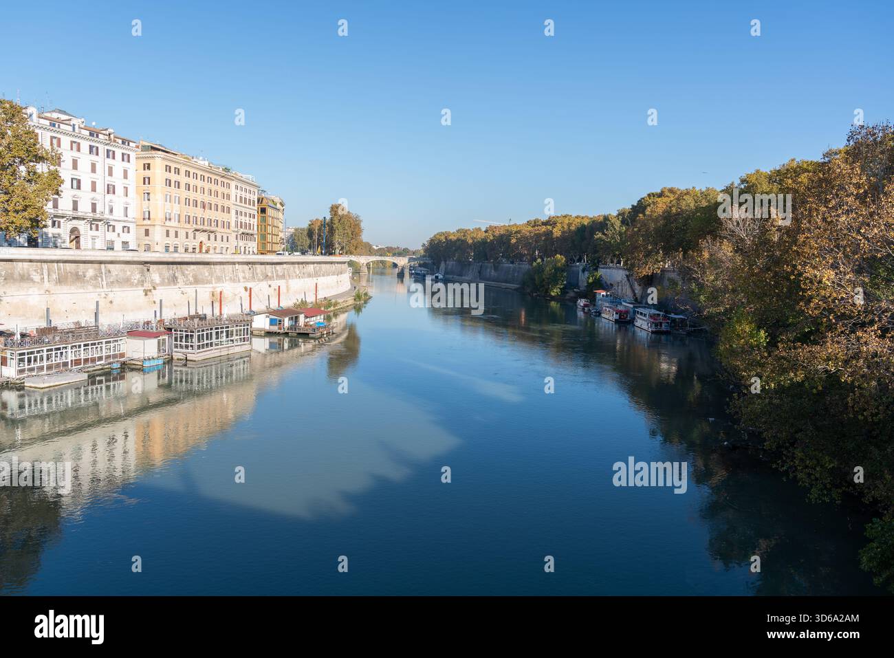 Ruhiger Blick auf den Tiber in Rom von einer Brücke aus, mit ruhigem Wasser, ohne Menschen, historischen Gebäuden am Ufer und ruhiger urbaner Atmosphäre. Stockfoto