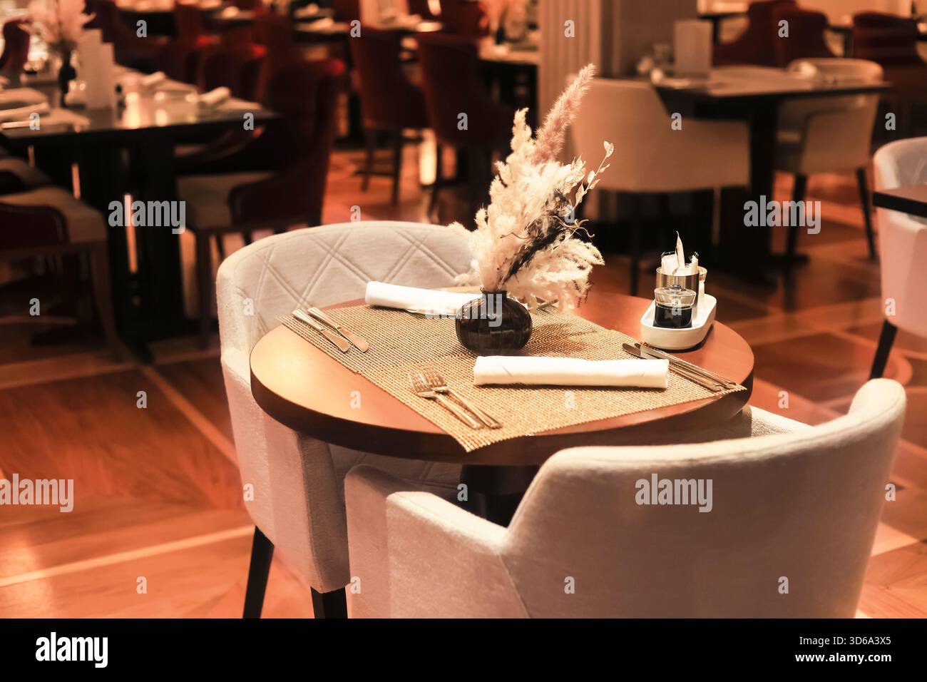 Ein elegantes Restaurant mit intimer Tischeinrichtung, weichen Stühlen, warmer Beleuchtung und dekorativem Trockengras. Hochwertige Fotos Stockfoto