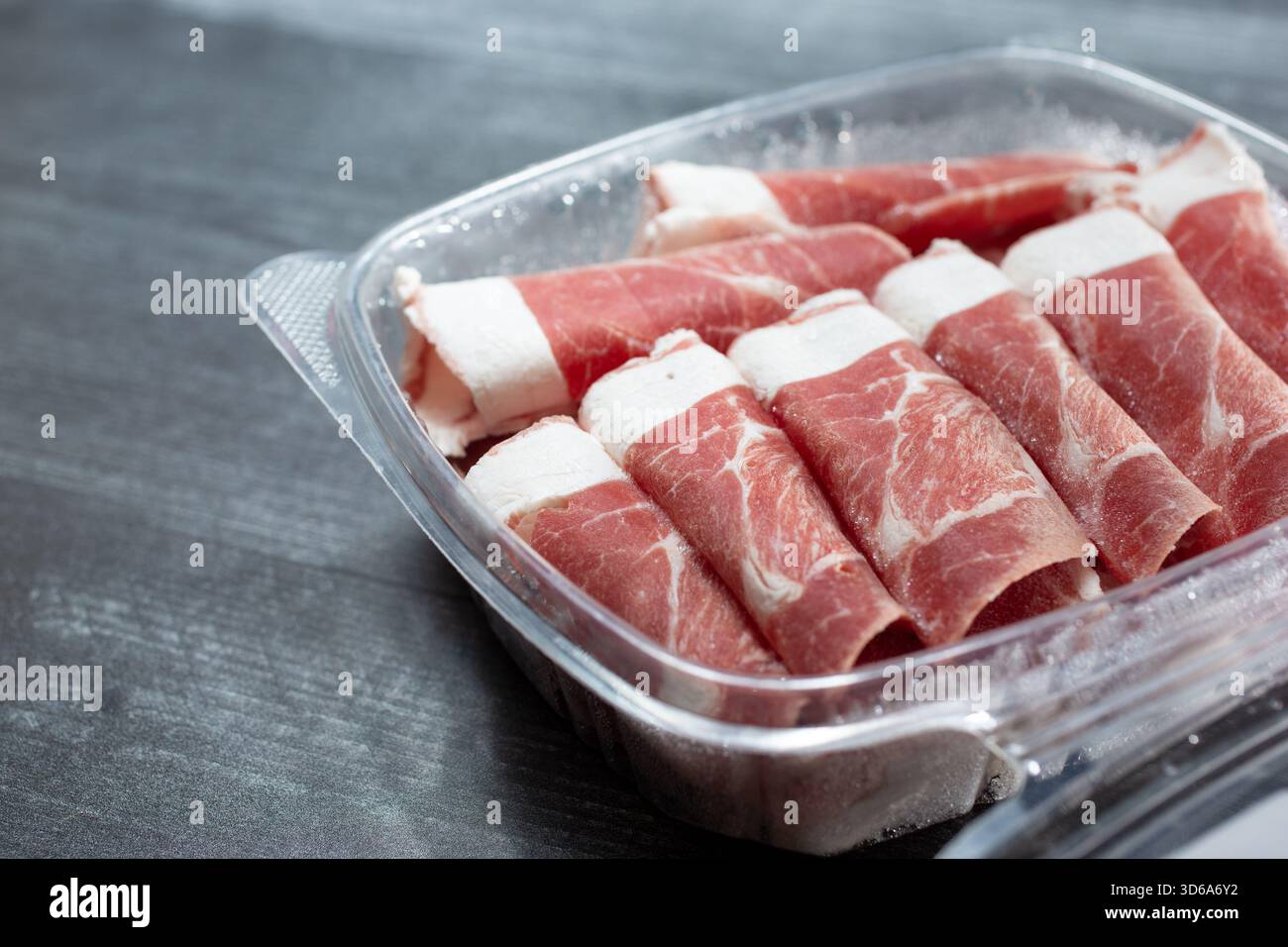 Eine Ansicht eines Kunststoffbehälters, gefüllt mit halbgefrorenen Scheiben australischer neuseeländischer Lammschulter. Stockfoto