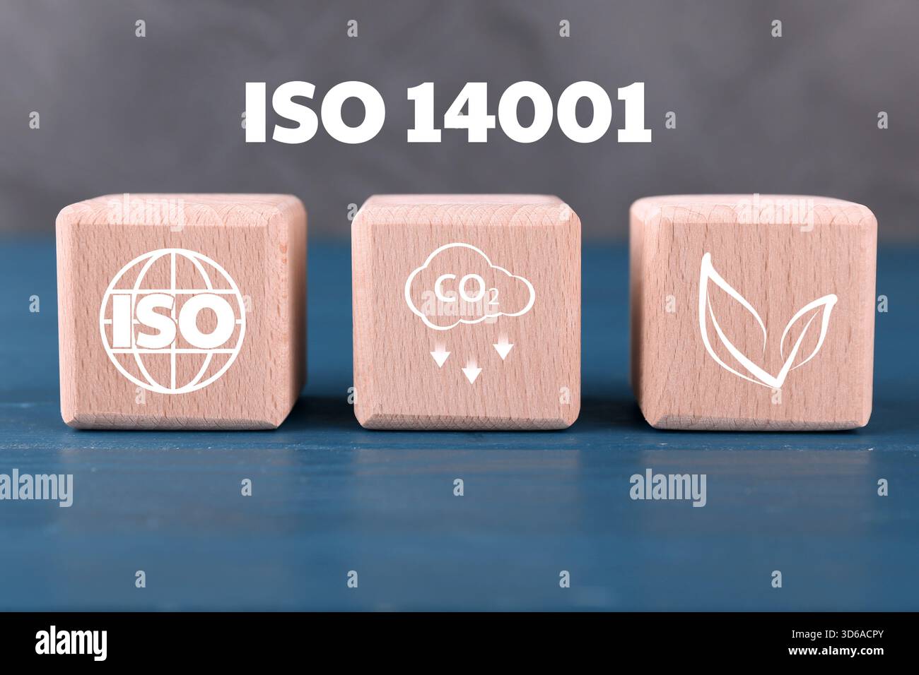 Umweltmanagementsysteme nach ISO 14001. Holzwürfel mit verschiedenen Symbolen auf blauem Tisch Stockfoto