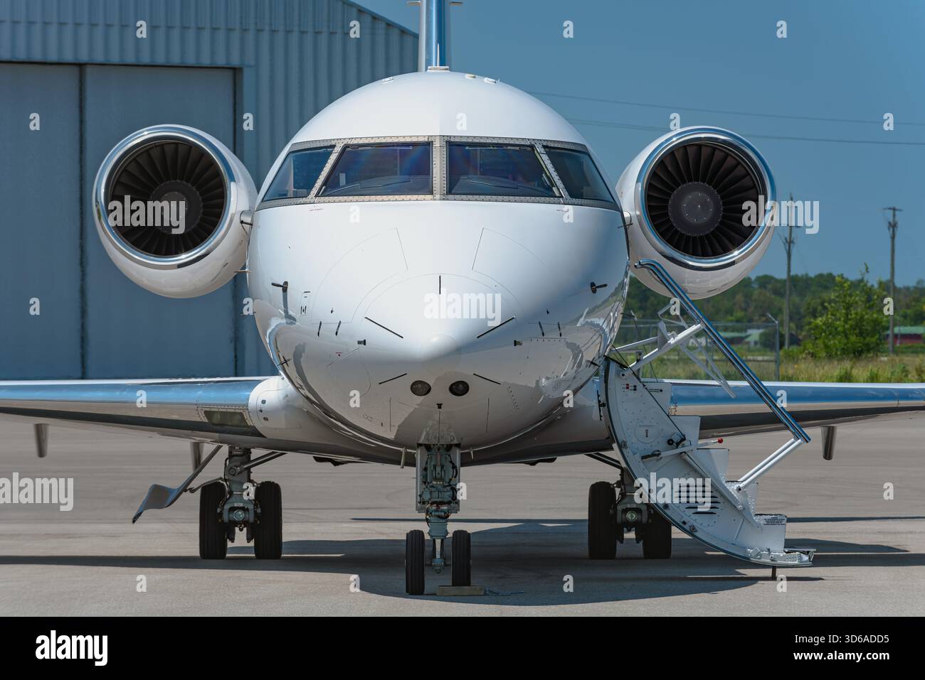 Frontansicht eines zweimotorigen Business-Jets auf der Flughafenrampe, fotografiert in Augenhöhe mit ausgefahrener Luftreppenklappe, und beide Motoren sind deutlich sichtbar Stockfoto