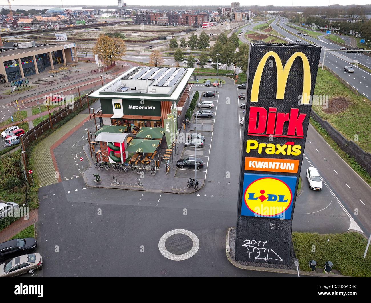 Harderwijk, Niederlande - 16. November 2025: McDonalds Restaurant mit Sitzplätzen im Freien, Parkplatz, großen Schildern im Einzelhandel und nahe gelegenen Autobahnverkehr, Stockfoto