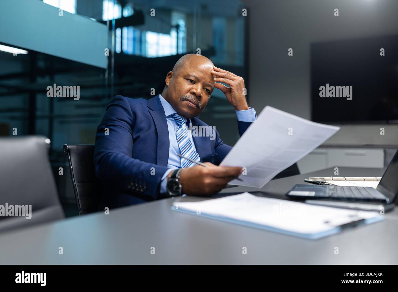 Seriöser reifer afroamerikanischer Geschäftsmann, der Dokumente in modernen Büros analysiert Stockfoto