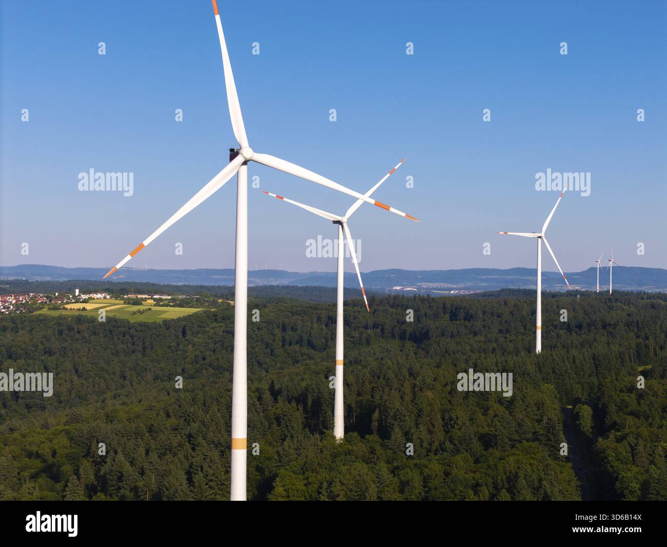 Drei Windräder erheben sich über einem grünen Wald unter klarem Himmel bei Schorndorf, Remstal, Baden-Württemberg Stockfoto