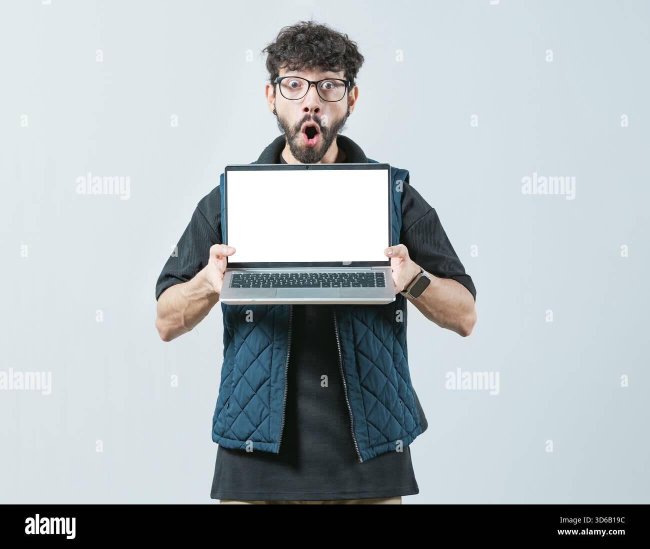 Ein hübscher Mann mit einer Brille, der eine Werbeaktion auf dem Laptop-Bildschirm anzeigt. Porträt eines bärtigen, gutaussehenden Mannes, der den Laptop isoliert zeigt Stockfoto