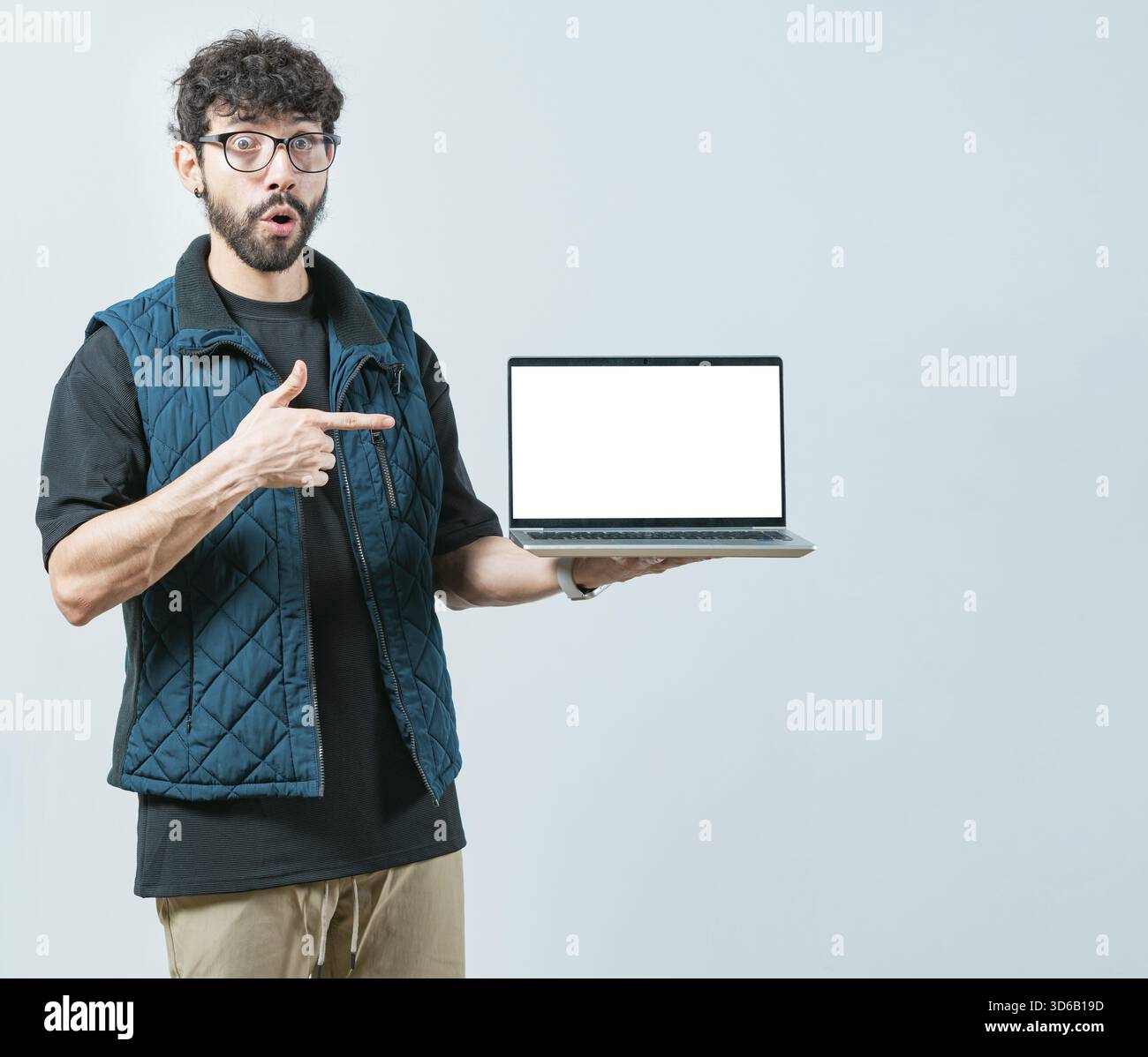 Porträt eines bärtigen, gutaussehenden Mannes, der den Laptop isoliert zeigt. Ein hübscher Mann mit einer Brille, der eine Promotion auf dem Computerbildschirm anzeigt Stockfoto