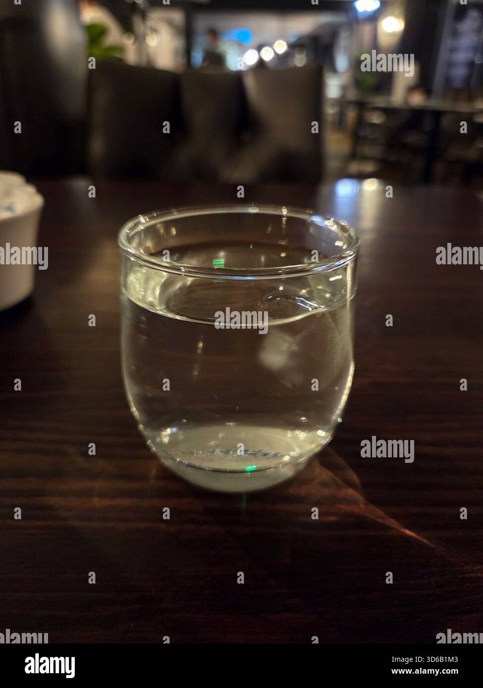Ein Glas Wasser auf einem dunklen Holztisch - Smartphone-aufgenommenes Stockfoto