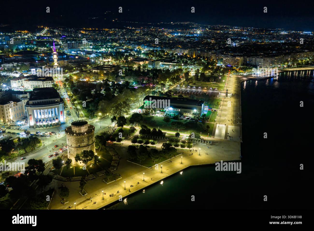 Thessaloniki, Griechenland, 27. Oktober 2025. Der Weiße Turm leuchtet am Meer, während Geschichte und Nachtleben entlang der Uferpromenade in einer Stadt verschmelzen, die nie aufhört Stockfoto