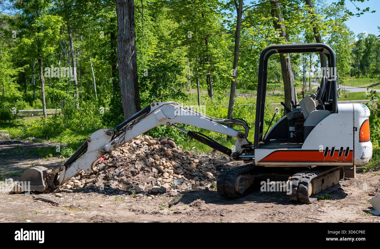 Ein Minibagger auf Schmutz in der Nähe eines Steinhaufens auf einem neuen Bauplatz. Stockfoto