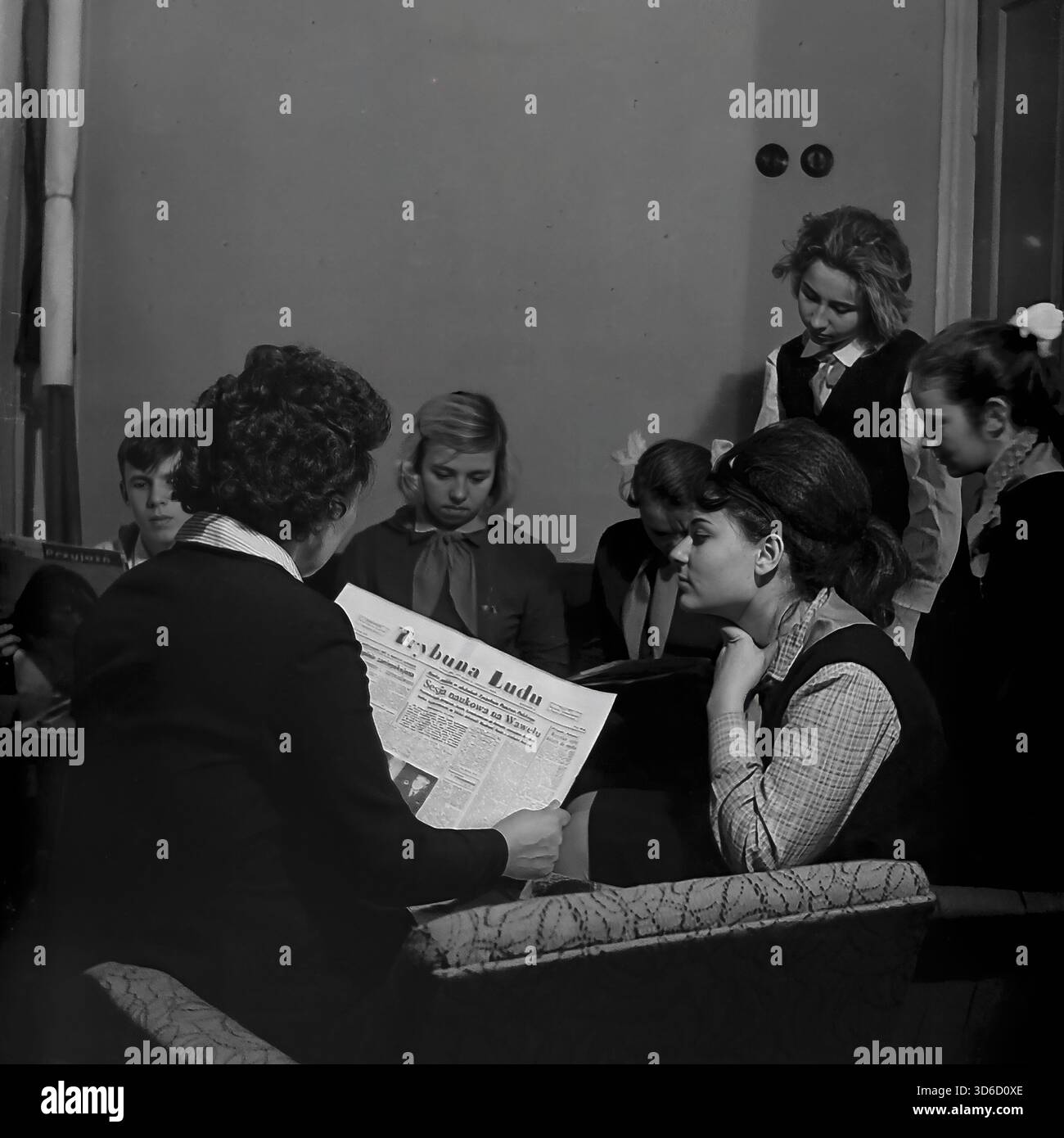 Slawjansk, Ukraine, UdSSR - 1970er Jahre: Authentisches Archivfoto einer politischen Informationsveranstaltung im Polnisch-sowjetischen Freundschaftsraum. Eine Lehrerin liest die polnische Zeitung Trybuna Ludu vor einer Gruppe aufmerksamer Schüler, die in Sesseln sitzen. In der sichtbaren Überschrift wird "Sesja naukowa na Wawelu" erwähnt. Dieses Schwarzweiß-Bild fängt die ideologische Bildung, den Zugang zur ausländischen Presse und den kulturellen Austausch in der Donezker Region während der friedlichen Sowjetzeit ein. Stockfoto