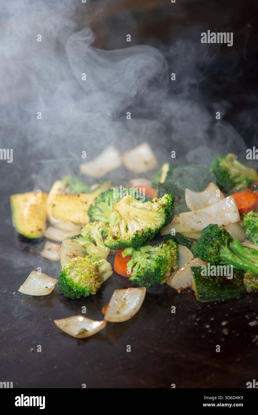 Ein Blick auf einen Haufen Gemüse, das auf einer Grillplatte kocht. Stockfoto