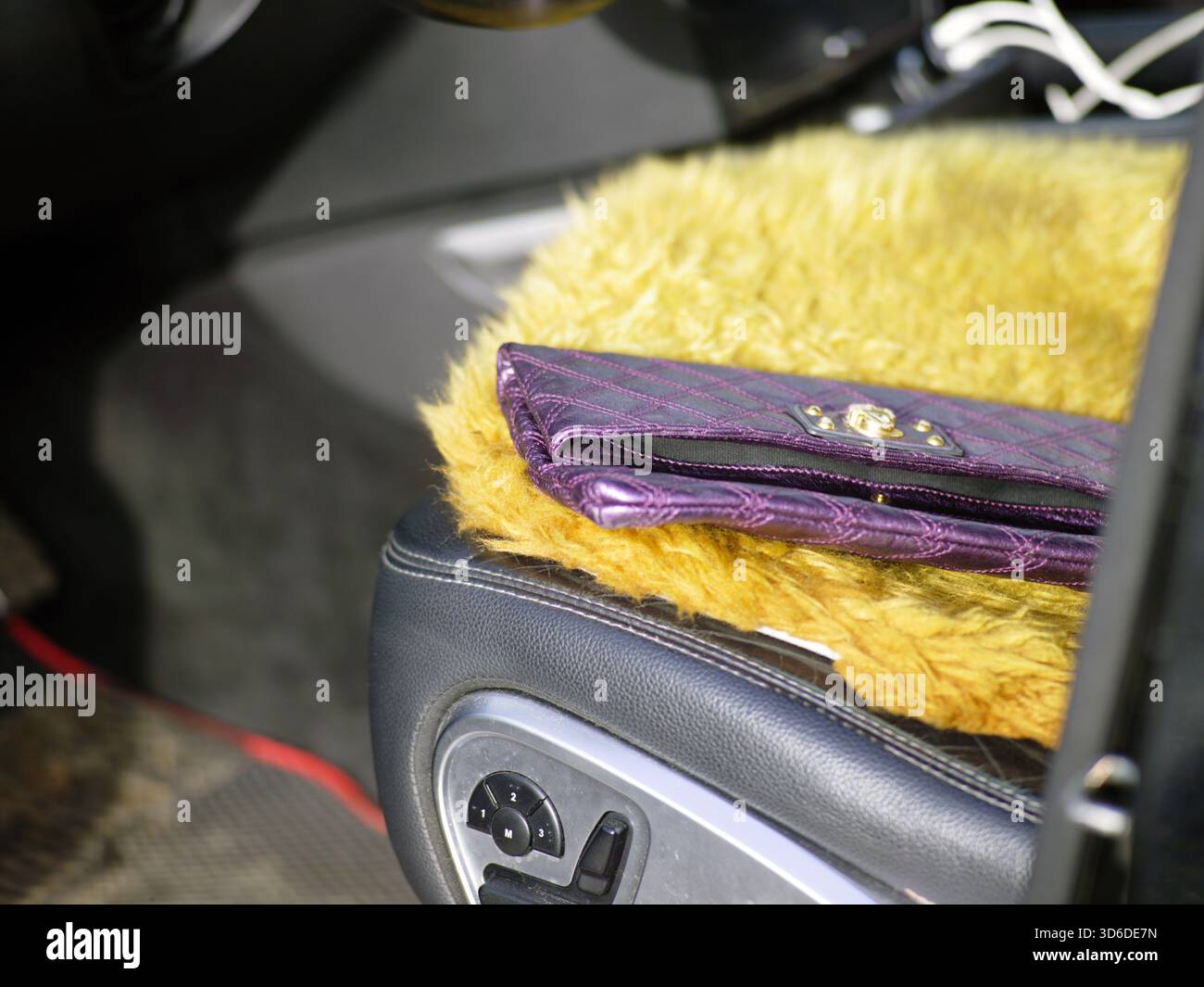 Eine purpurne Handtasche der Dame, die auf einem Autositz steht, Konzept der Vergesslichkeit Stockfoto