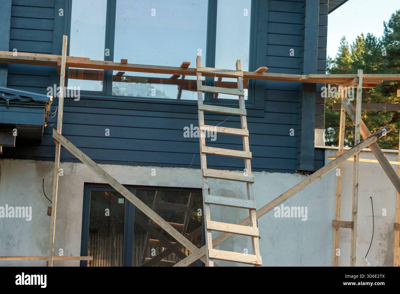 Ein Gerüst und eine Leiter aus Holz, die gegen das Haus gelehnt sind, keine Leute Stockfoto
