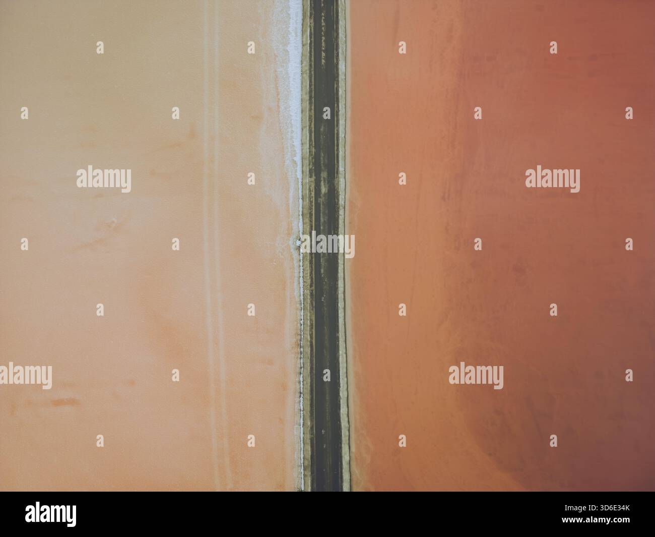 Aus der Vogelperspektive der rosa und roten Salzwiesen, die durch einen schmalen Landstreifen geteilt sind, Bacuta Salzwiesen, Huelva, Andalucía, Spanien. Stockfoto