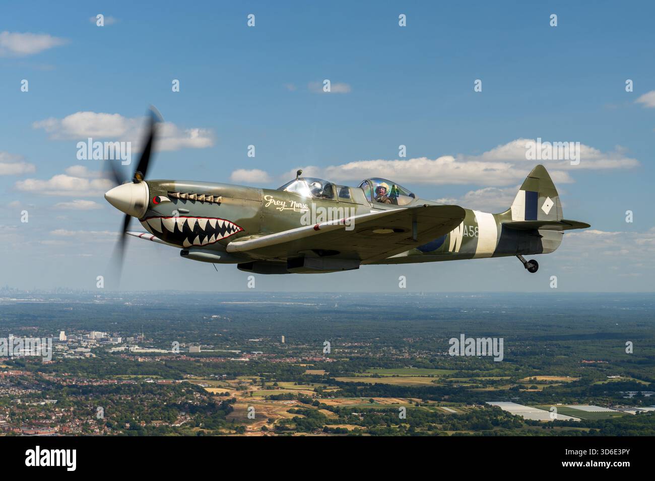 Hampshire, England - 09. August 2025: Aus der Vogelperspektive eines alten Kampfflugzeugs, das über einem Wandteppich aus üppigen grünen Feldern und dichten Wäldern aufsteigt, die Sonne glinti Stockfoto