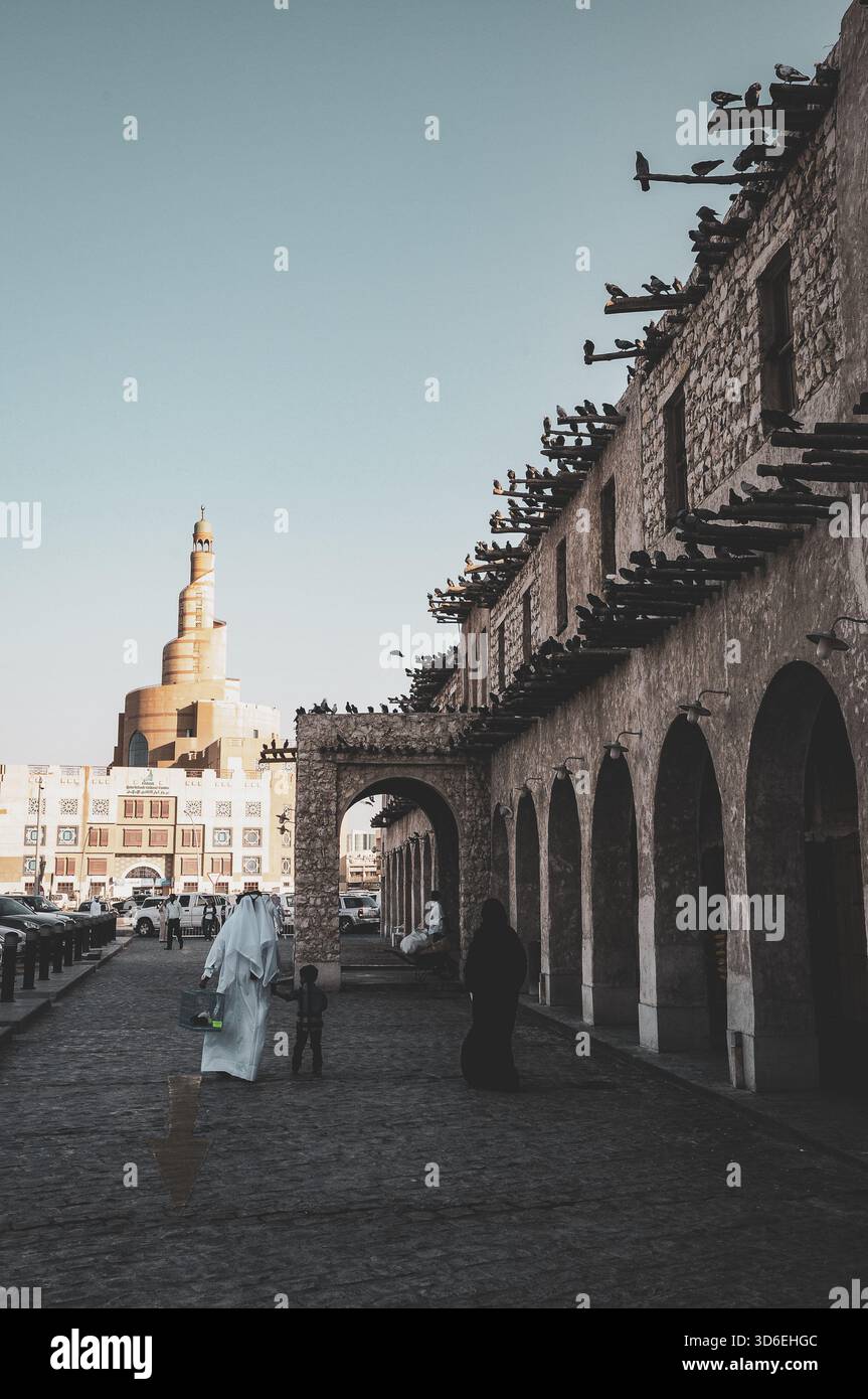 Souq Waqif, ein historischer Marktplatz in Doha, Katar. Das markante spiralförmige Minarett des islamischen Kulturzentrums Fanar - Katar ist sichtbar Stockfoto