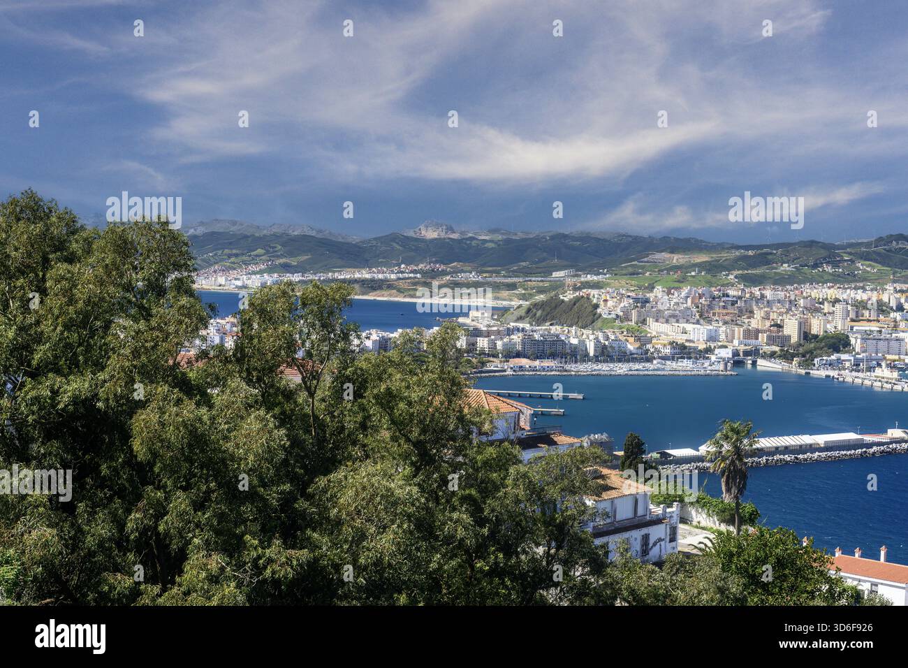 Weite Küstenlandschaft mit Ceuta, Hafeninfrastruktur und bergigem Gelände dahinter. Stockfoto