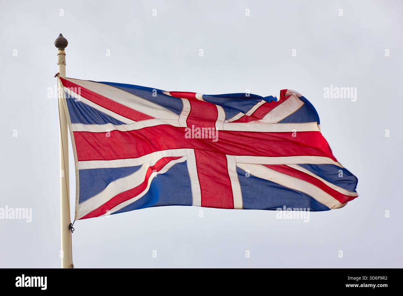 Union Jack Flag fliegt auf dem Pole gegen den hellen Himmel, Symbol für Großbritannien und Stolz Stockfoto