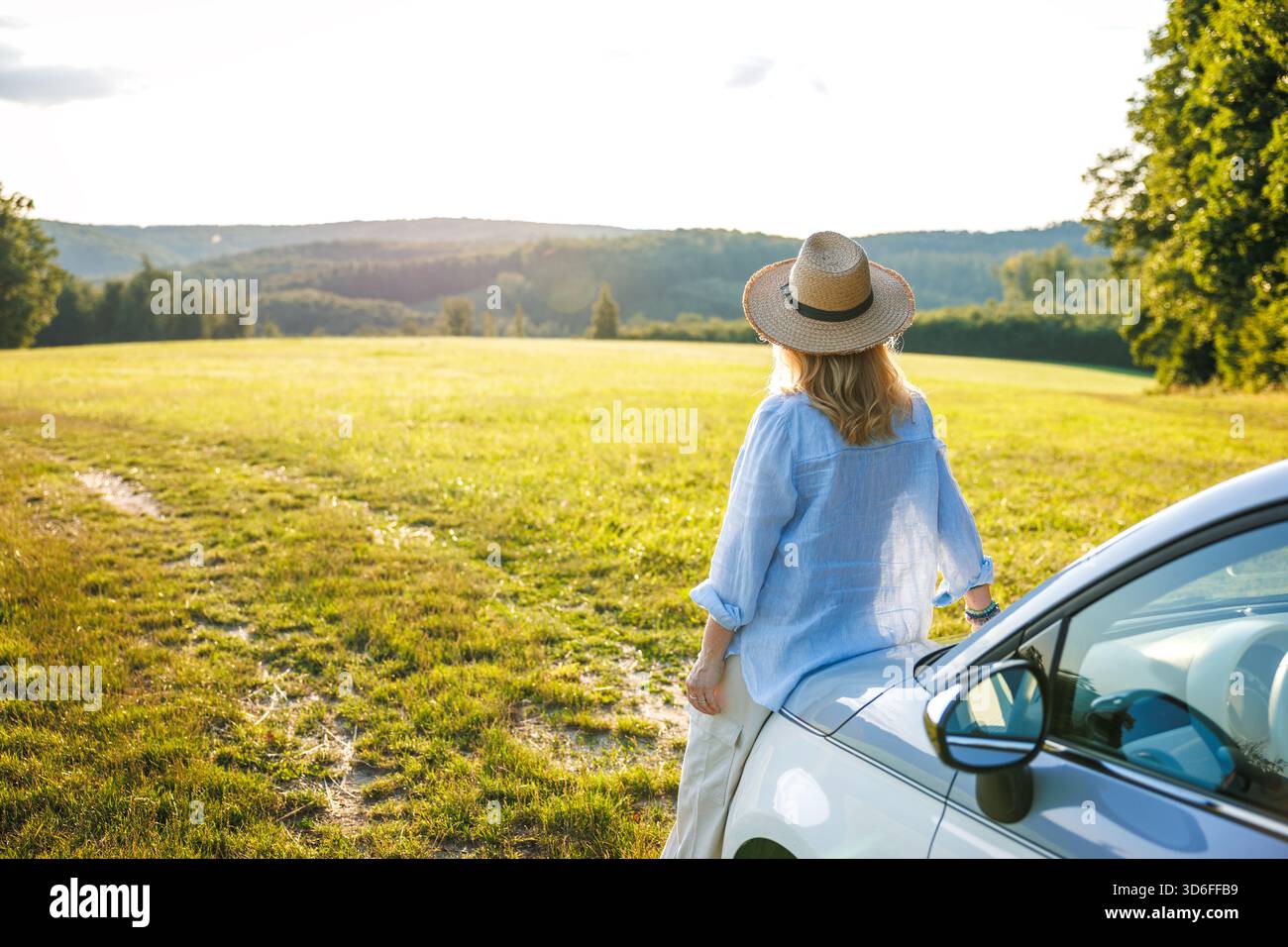 Frau ruht sich im Auto auf dem Land aus und macht eine Pause während einer Fahrt. Genießen Sie Sommerreisen und Reisefreiheit Stockfoto