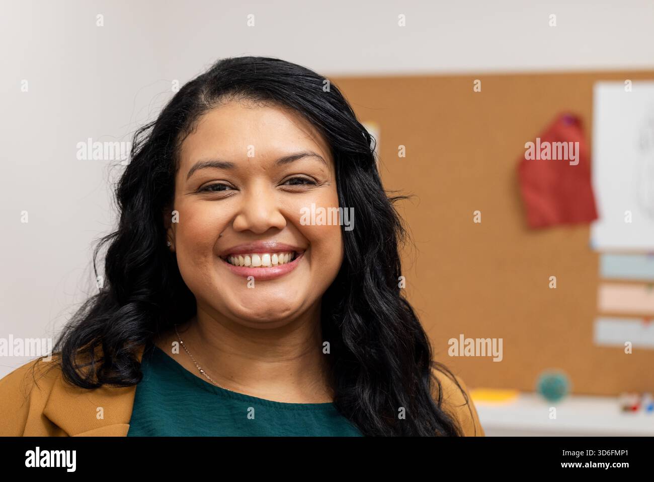 Frau, die im Büro steht und einen Blazer trägt, der Stressball an Korkbrett mit festgehaltenem rotem Tuch hält Stockfoto