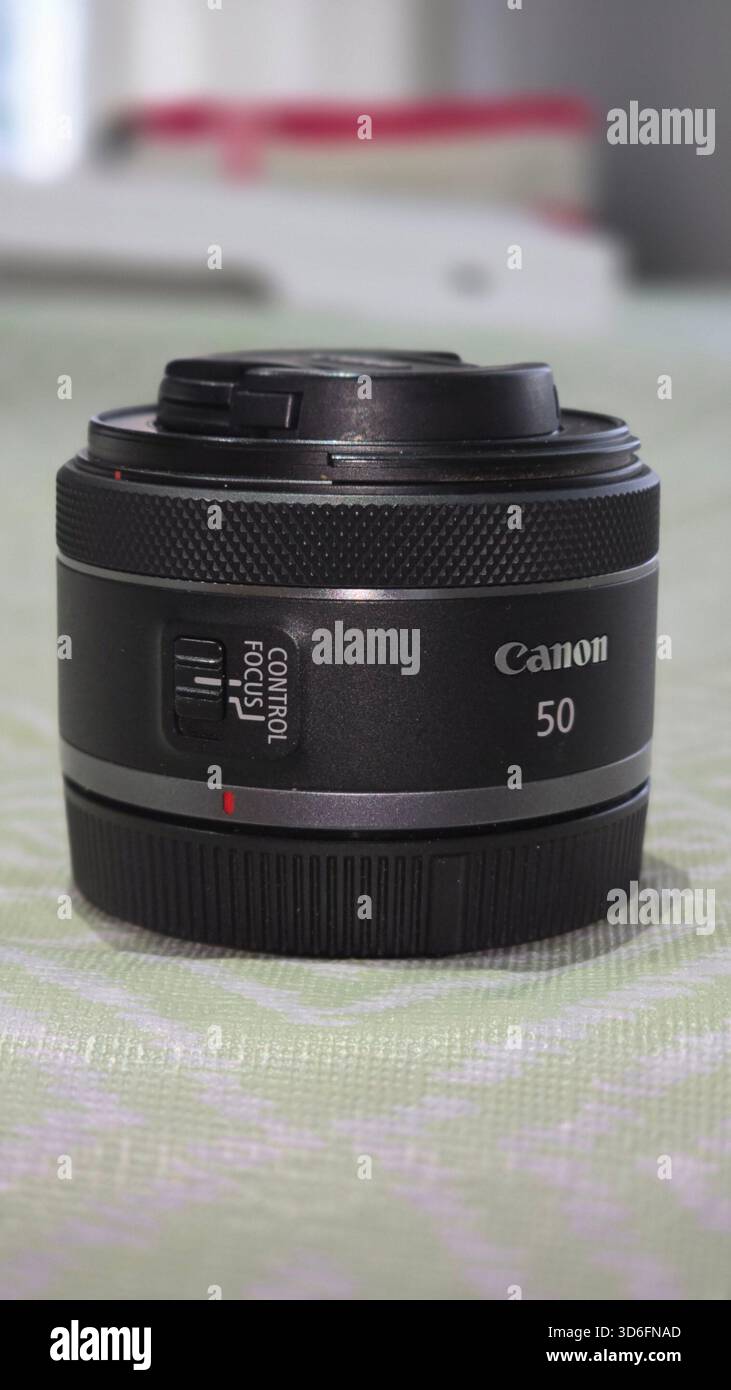 Das 50-mm-Objektiv von Canon liegt auf einer gemusterten Oberfläche mit geringer Schärfentiefe auf und unterstreicht den AF/MF-Schalter und das schlanke Design. Stockfoto