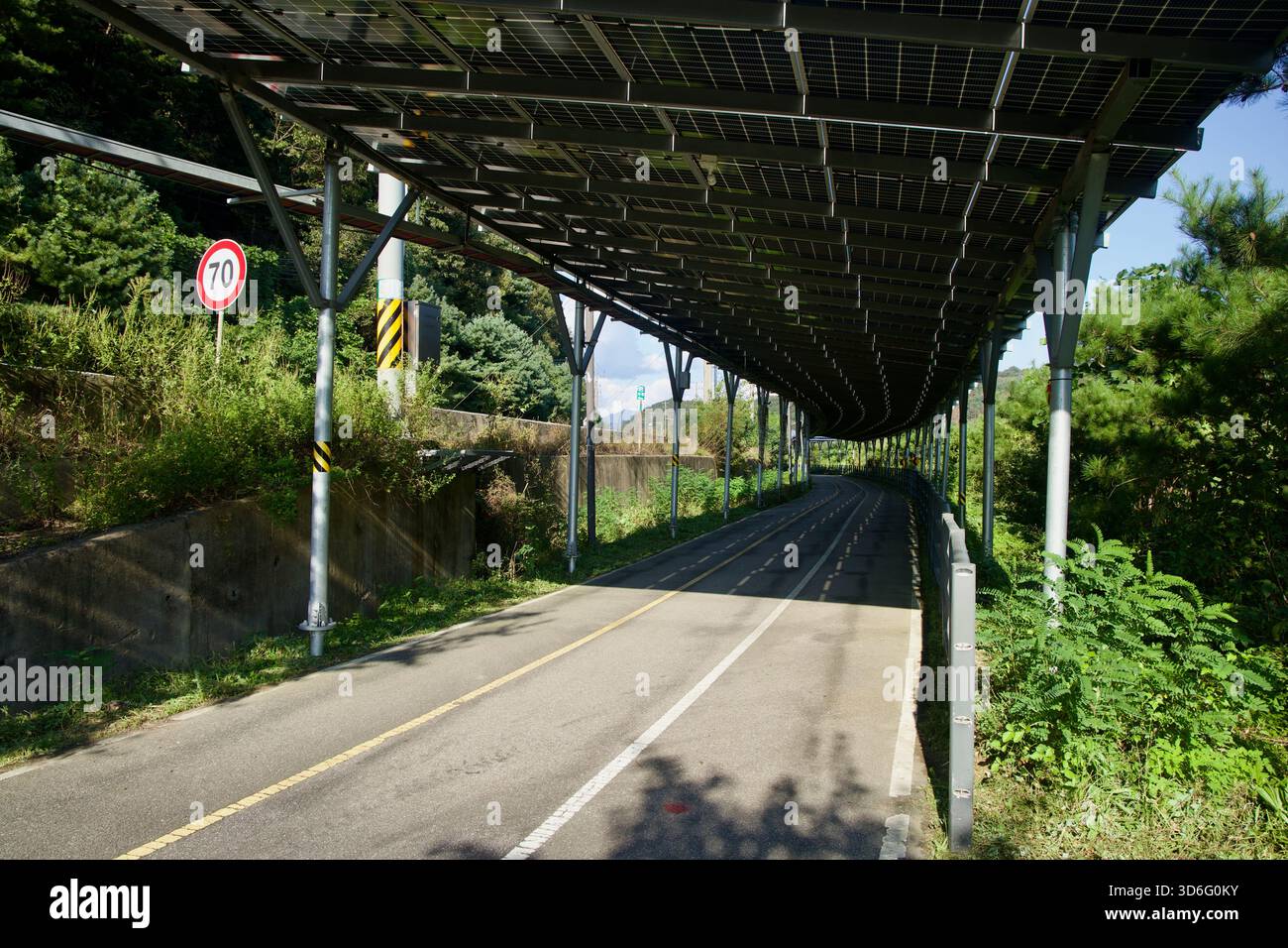 Ein langes Photovoltaik-Baldachin umhüllt einen zweispurigen Abschnitt des Bukhangang Bike Path neben dem Daljeon Stream in Gapyeong mit einem roten 70 Geschwindigkeitsbegrenzungsschild Sta Stockfoto