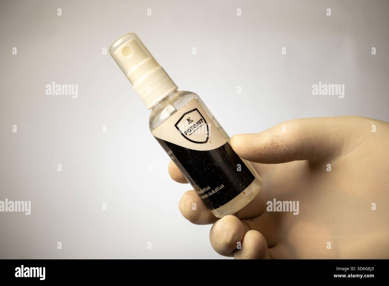 Handschuhe präsentieren eine kleine Sprühflasche mit fotokatalytischem Oberflächenschutz von FOTONIT. Stockfoto