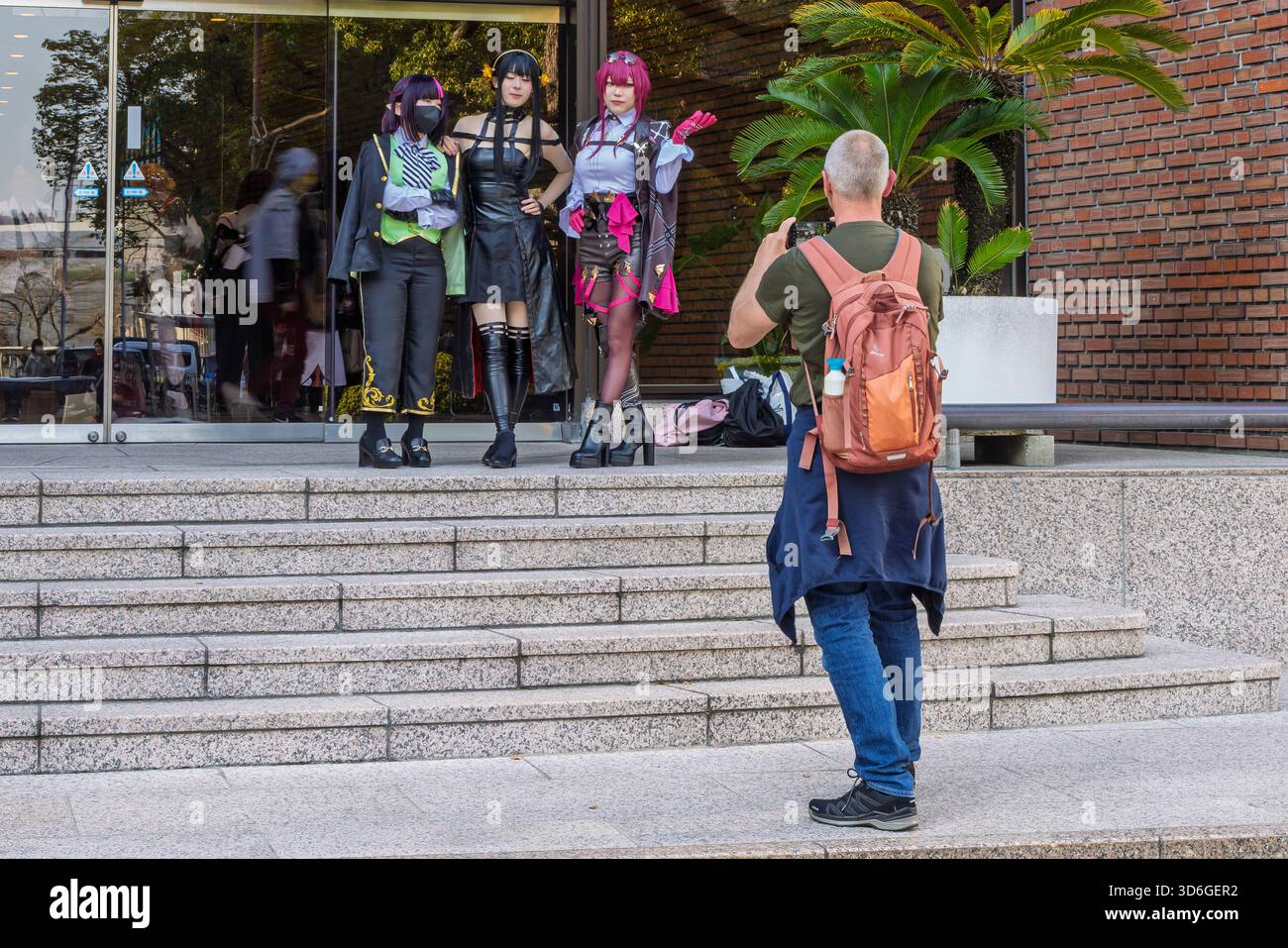 Nagasaki, Japan - 23. März 2025: Männliche Touristen fotografieren drei posierende Anime-Mädchen, Beispiel für Cosmo-Kultur, Fans als Charaktere verkleidet, Nagasaki in Jpan Stockfoto