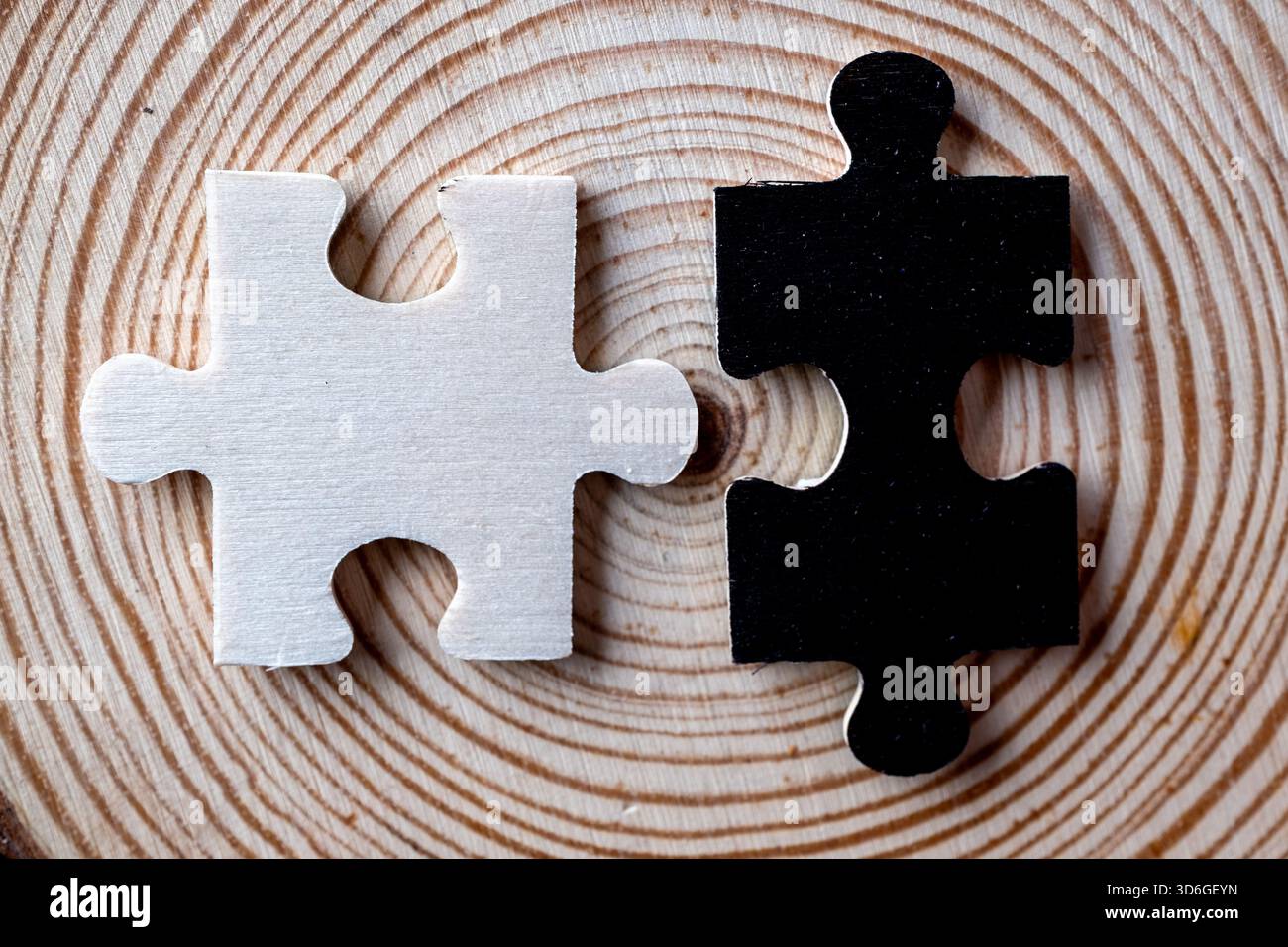 Makrokontrast: Schwarz-weiße Puzzleteile, die auf einer holzigen Oberfläche mit Wachstum ausgerichtet sind Stockfoto
