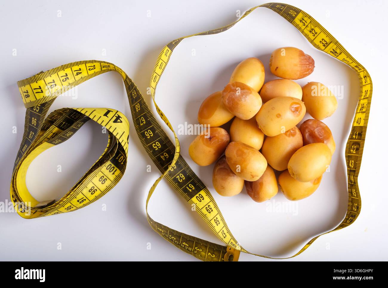 Ein Teller mit kleinen Kartoffeln, umgeben von einem Maßband, das Gesundheit und Ernährung symbolisiert Stockfoto