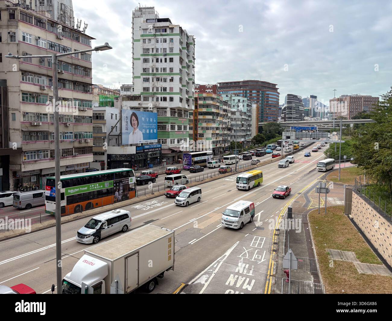 Eine mehrspurige Stadtstraße in Hongkong ist voll von Autos, Doppeldeckerbussen und Lieferwagen, flankiert von hohen Wohn- und Geschäftsgebäuden darunter Stockfoto