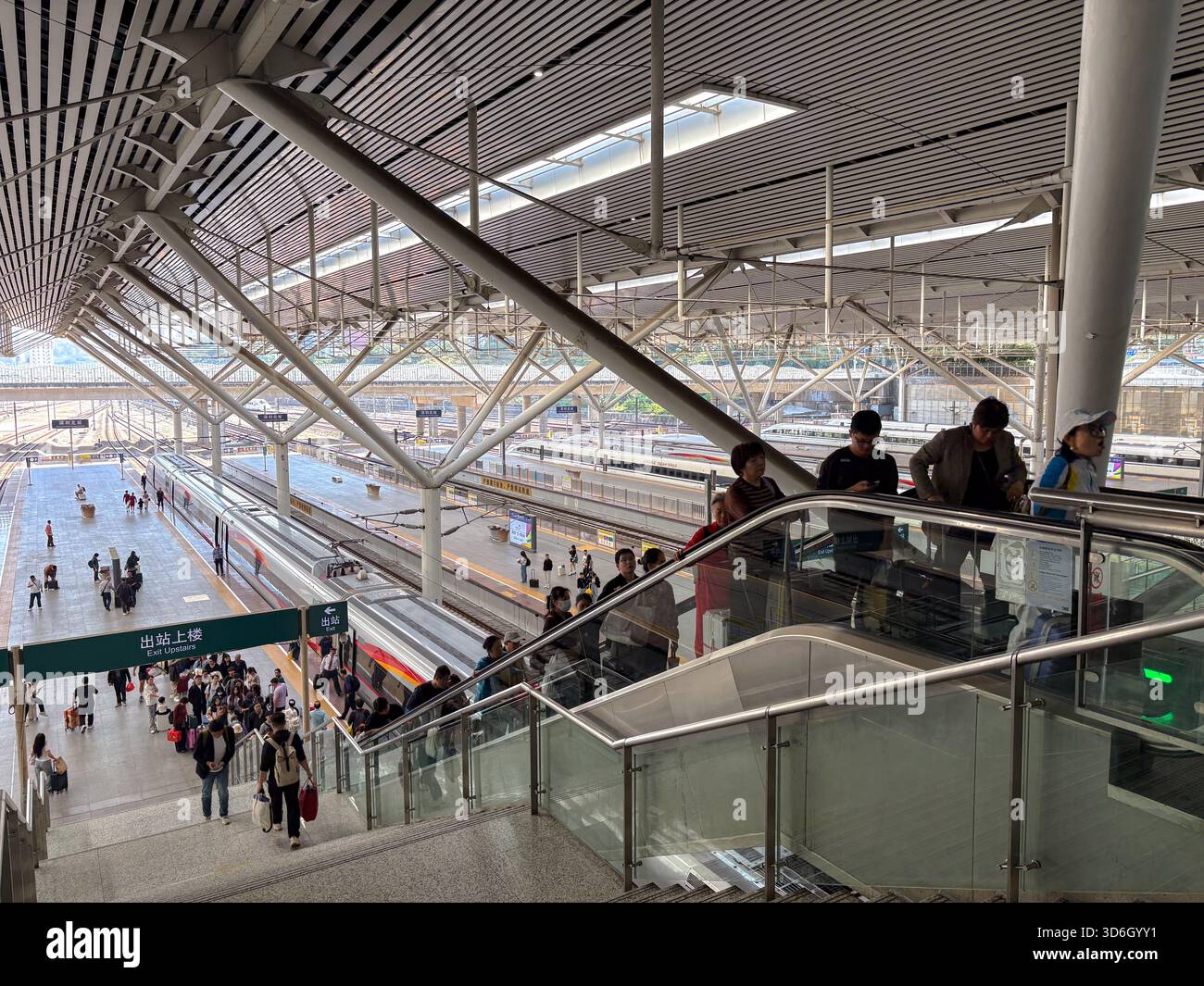 Shenzhen North Railway Station, ein wichtiger Hochgeschwindigkeitsbahnknotenpunkt in China, mit Passagieren, die Bahnsteige und Rolltreppen unter seiner modernen Dachkonstruktion steuern Stockfoto
