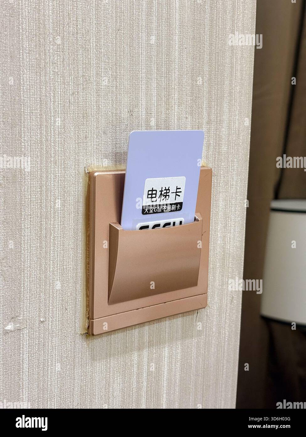 Eine Hotelschlüsselkarte, die in einen an der Wand montierten Netzschalterhalter gesteckt wird und die Elektrizität im Zimmer aktiviert. Dieses System ist für Energiesparer üblich Stockfoto