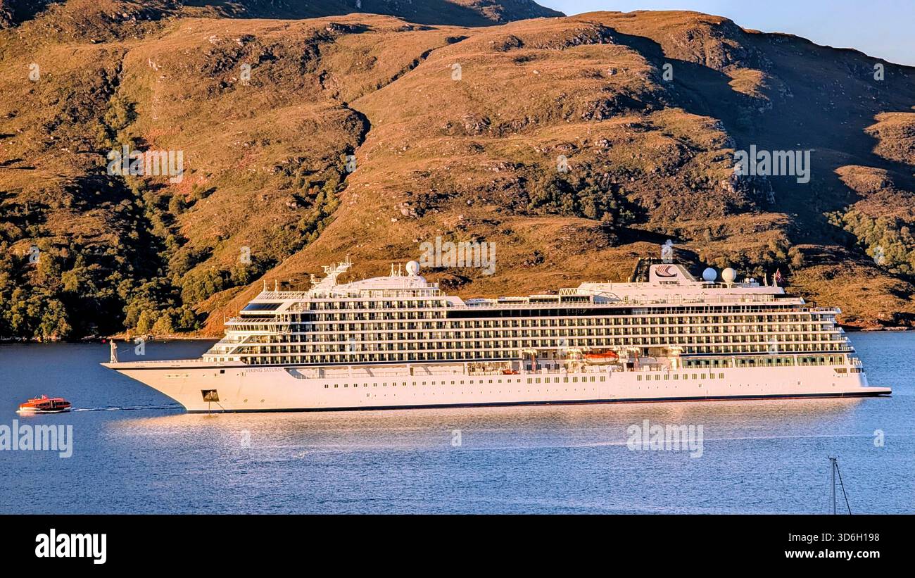 Großes Kreuzfahrtschiff vor Anker in Loch Broom, Ullapool am Sommermorgen, mit einem kleinen Boot im Vordergrund und Highland Hills im Hintergrund Stockfoto