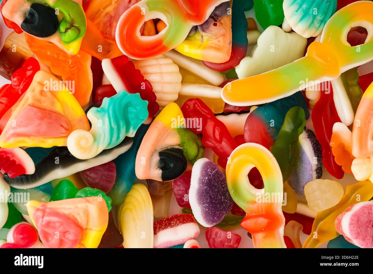 Kreativer Hintergrund aus gummiartigen Bonbons. Minimales trendiges Gummikonzept. Gelee-Süßigkeiten-Ästhetik. Farbenfrohe flache Lagen. Draufsicht. Stockfoto