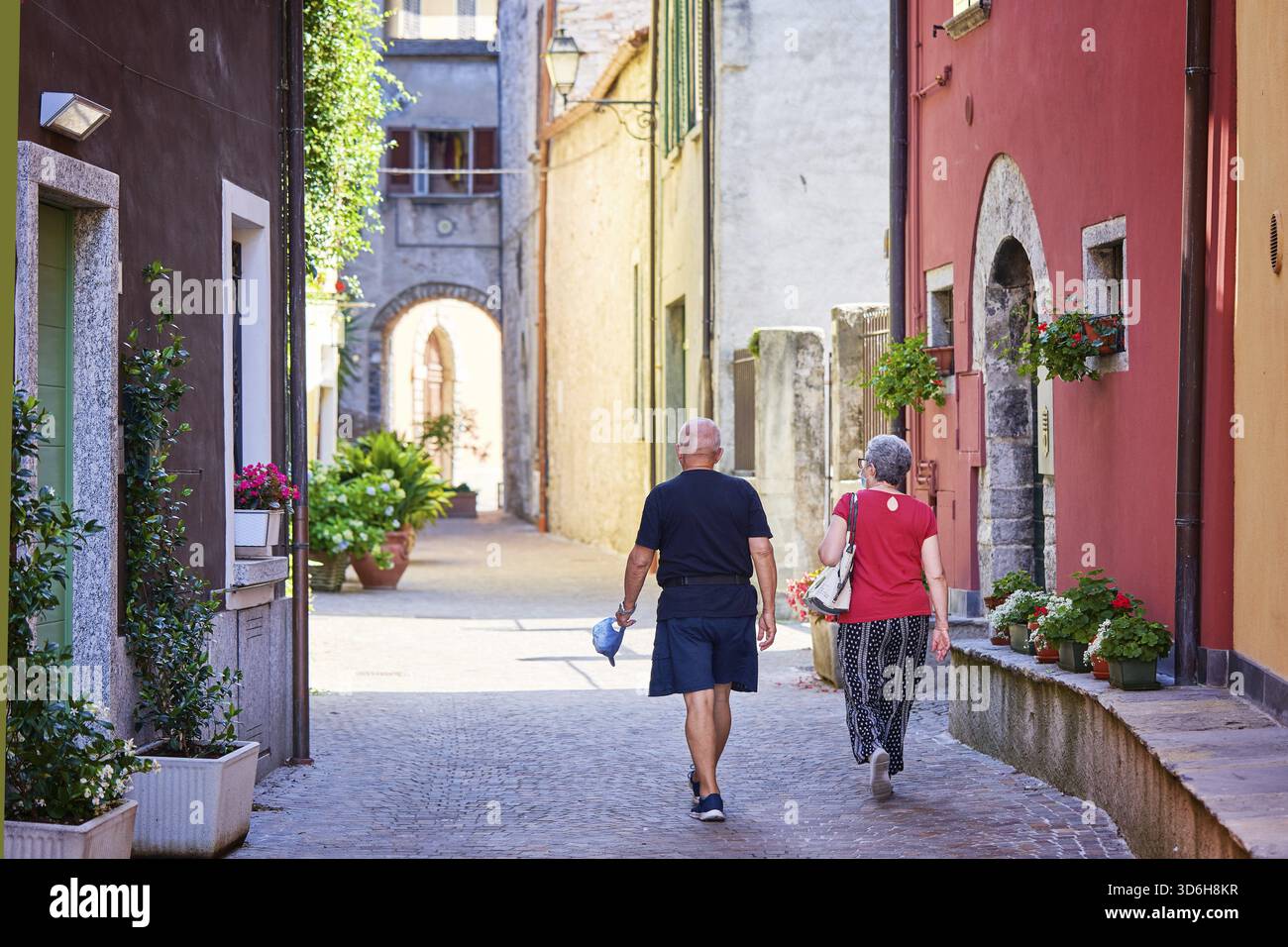 Mandello del Lario, Italien - 26. Juli 2020. Seniorenpaar, das zusammen reist und im Sommer im italienischen Dorf spazierengeht. Aktive ältere Menschen und ein Lebensstil auf Reisen Stockfoto