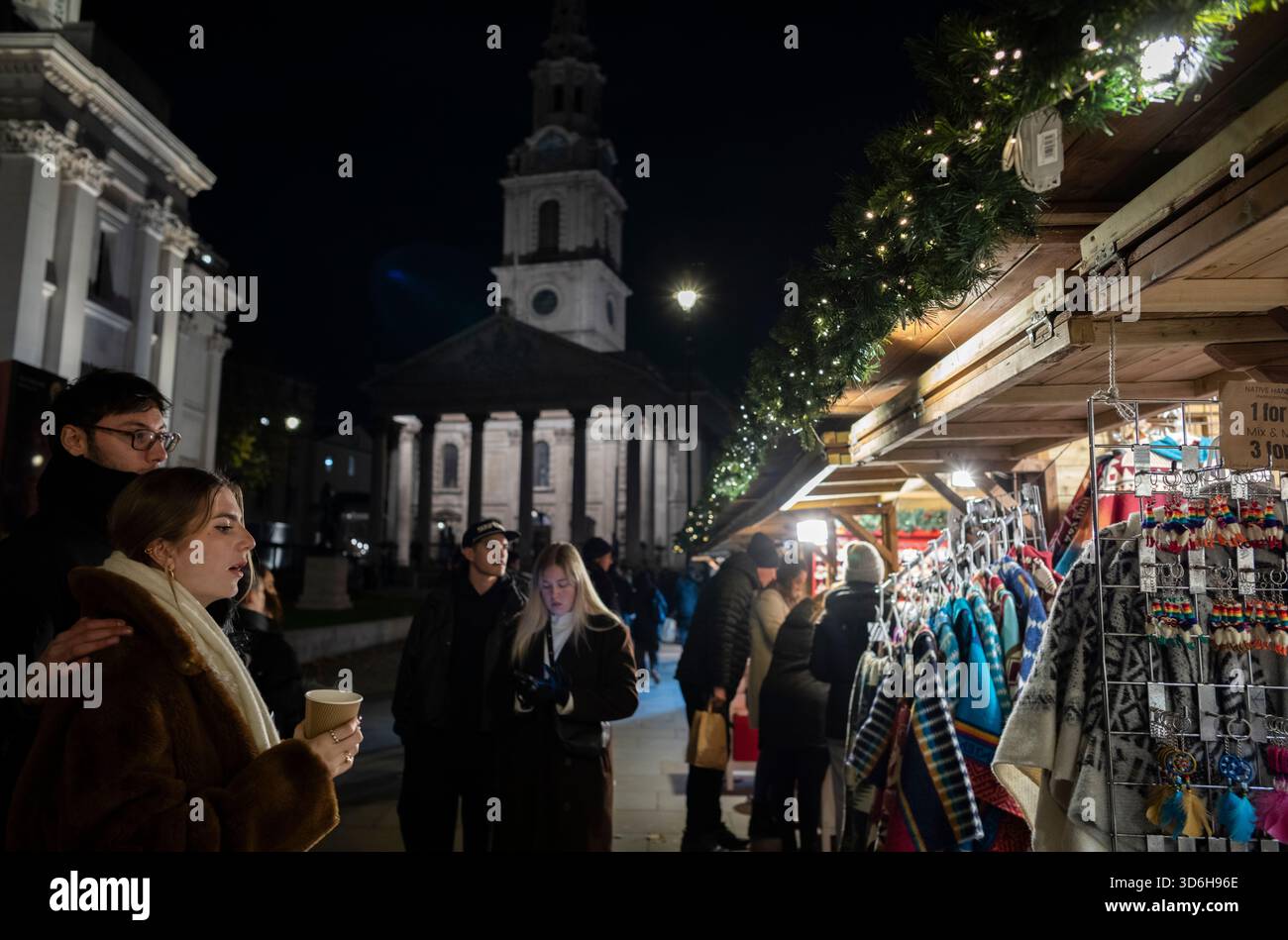 Weihnachten in London 2025 genießen Touristen die Feierlichkeiten auf dem Londoner Weihnachtsmarkt am Trafalgar Square in London, England, Großbritannien Stockfoto