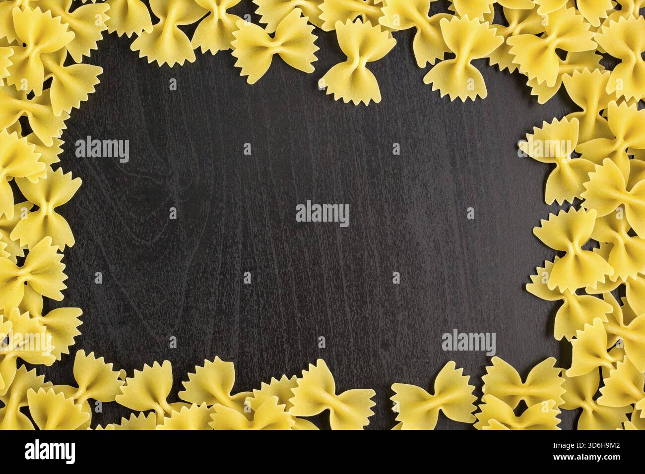 Essen, Rahmen Eines Stapels Farfalle Pasta auf dunklem schwarzem Hintergrund mit Copyspace Stockfoto