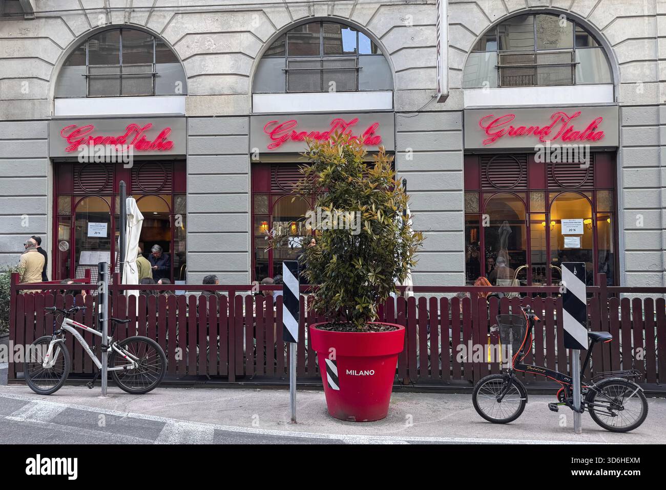 Mailand, Italien - 07. April 2025: Restaurant Gran Italia mit rotem Neonschild und Terrasse. Fahrräder und rote Pflanzgefäße auf der Straße Stockfoto