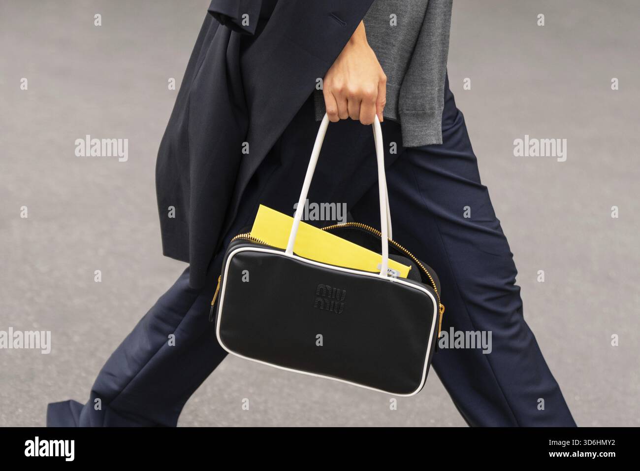 Paris, Frankreich - 11. März 2025: Schwarz-weiße Miu Miu-Tasche mit marineblauer Hose. Details zum Street-Style-Outfit Stockfoto
