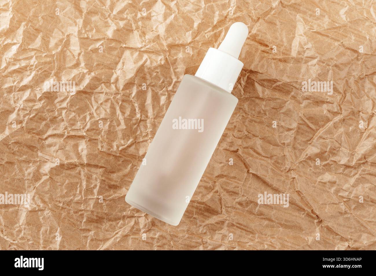 Hyaluronsäure-Tinktur auf gefaltetes Karton. Serum mit Kollagen und Peptiden auf zerknittertem Papier. Anti-Age-Produkt, Luxus-Körperpflege-Konzept Stockfoto